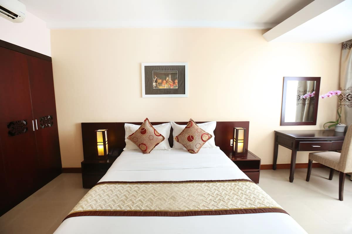 A hotel room with a large bed, two nightstands, a desk, and a chair.