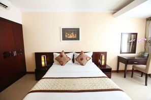 A hotel room with a large bed, two nightstands, a desk, and a chair.