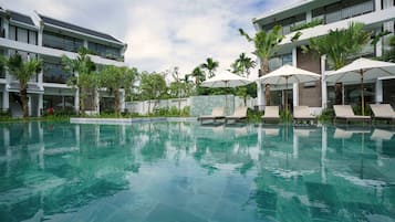 Una piscina al aire libre, sombrillas, sillones reclinables de piscina