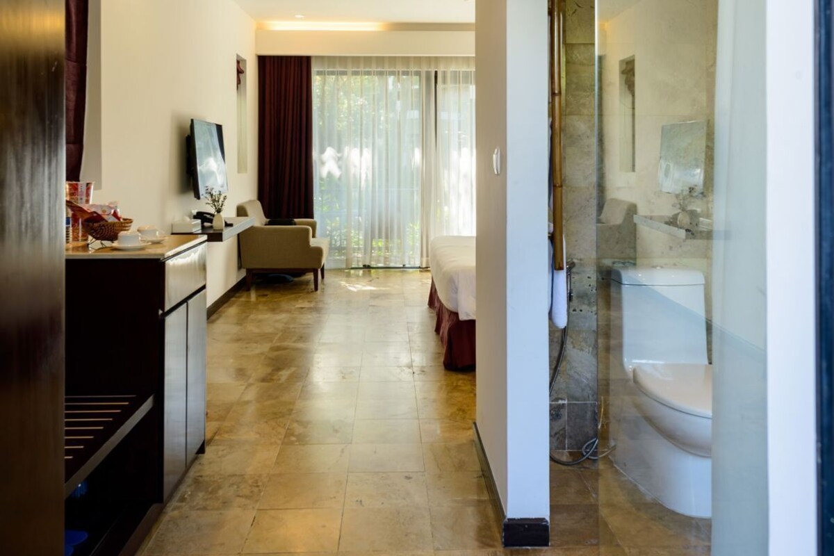 A hotel room with a bed, a desk, a TV, a bathroom with a bathtub, and a large window.