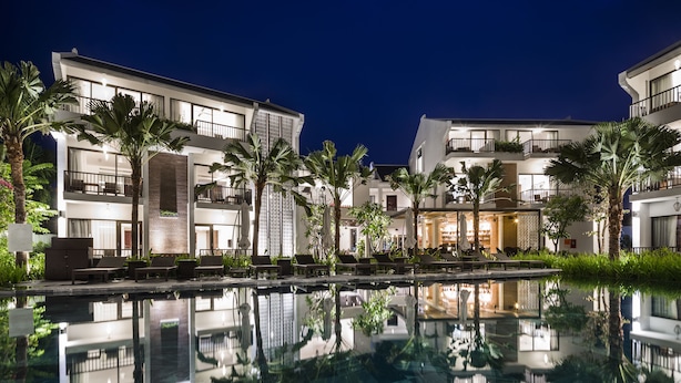 A modern hotel with multiple balconies, a swimming pool, and lush greenery. - Senvila Boutique Resort & Spa (Da Nang)