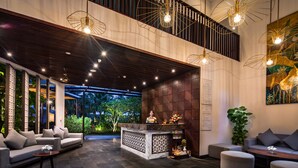 A modern lobby with a reception desk, seating area, and large windows overlooking greenery. - Senvila Boutique Resort & Spa (Da Nang)