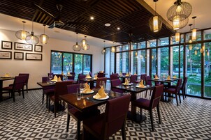 Un restaurante con mesas dispuestas para comer, amplios ventanales y lámparas colgantes.