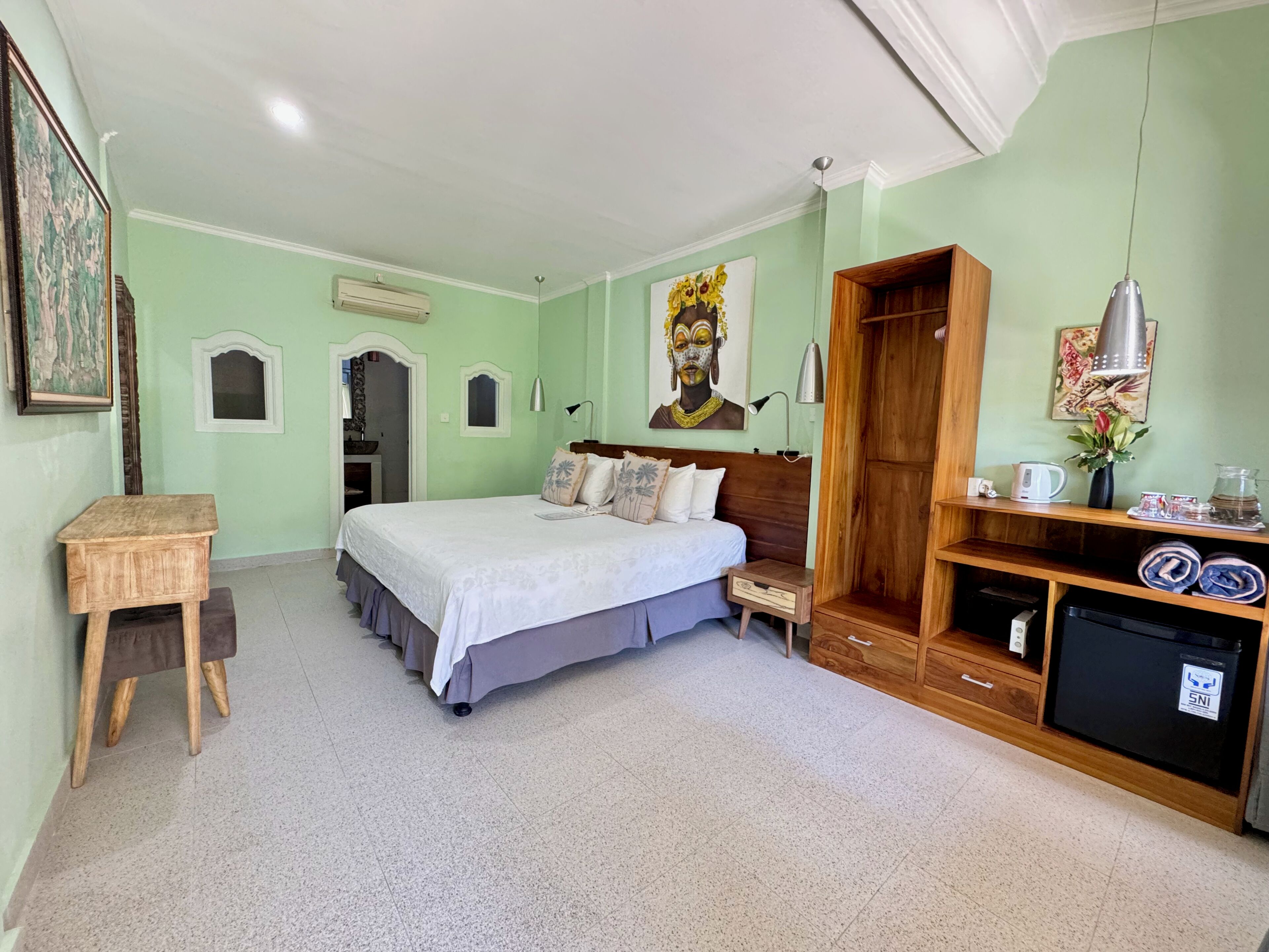 A bedroom with a bed, bedside table, wardrobe, and a small desk.
