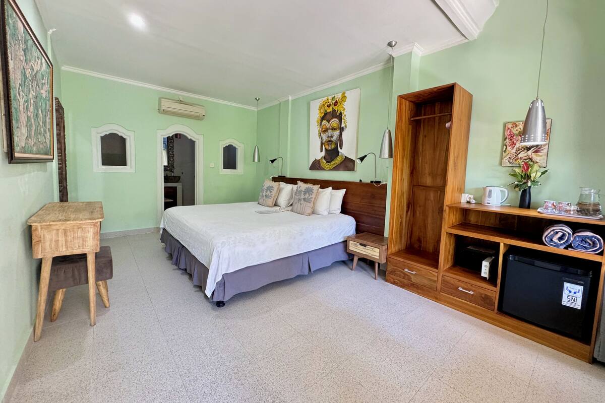 A bedroom with a bed, bedside table, wardrobe, and a small desk.