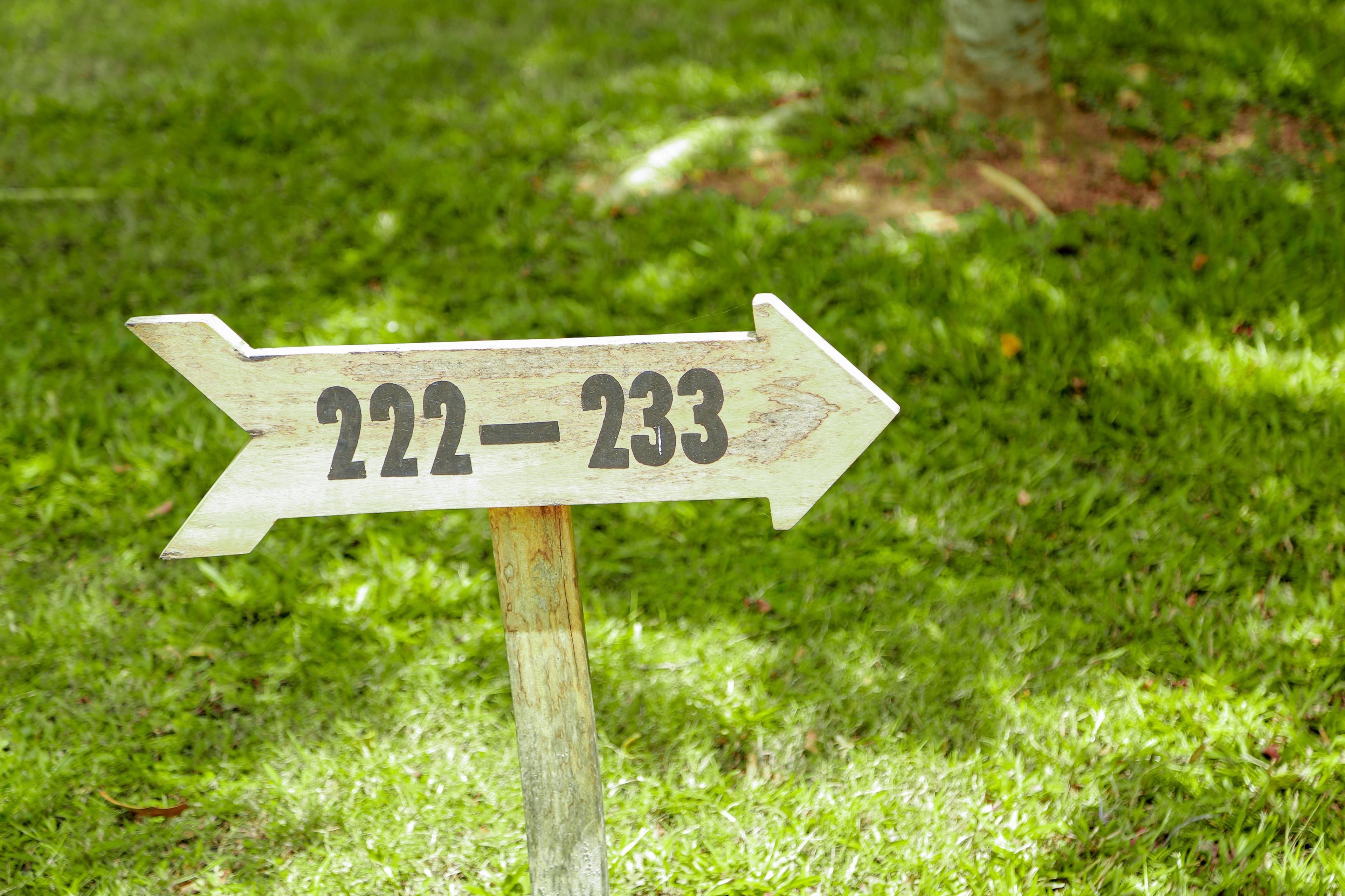 A wooden directional sign with numbers 222-233.