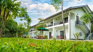 Un hotel de varios pisos con asientos al aire libre, un paraguas verde y una escalera.