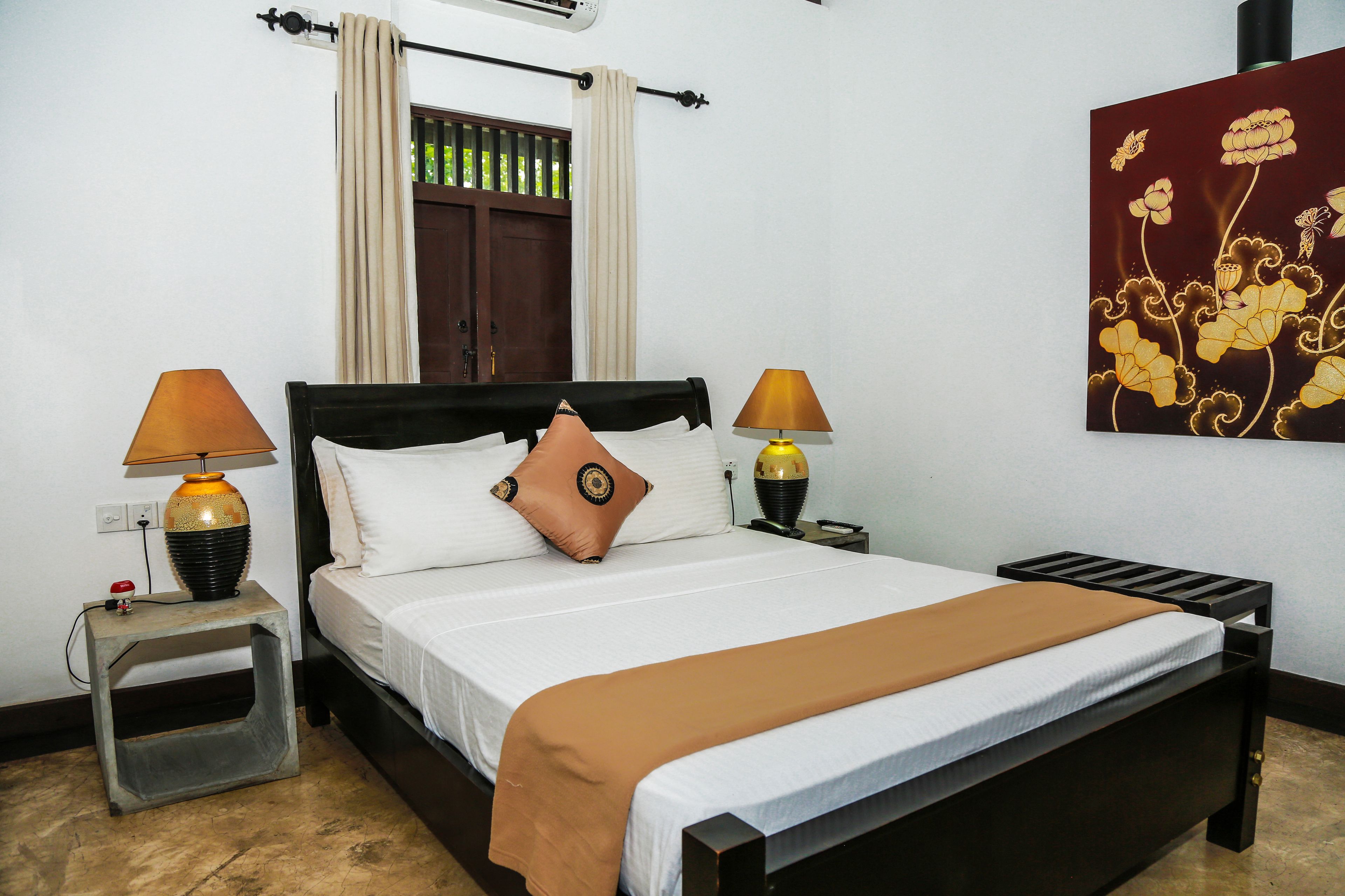 A neatly made bed with a brown blanket, two bedside lamps, and a decorative wall piece.
