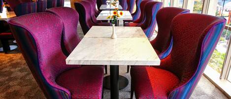 Un restaurante con sillas de estampado rojo y azul y una mesa de mármol.