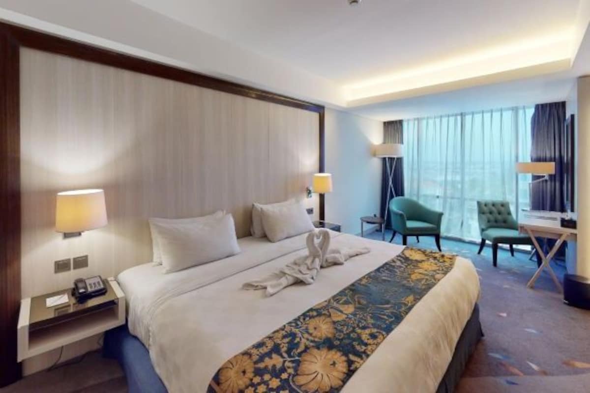 Una habitación de hotel con una cama grande, dos lámparas de noche, un escritorio con teléfono y una silla.