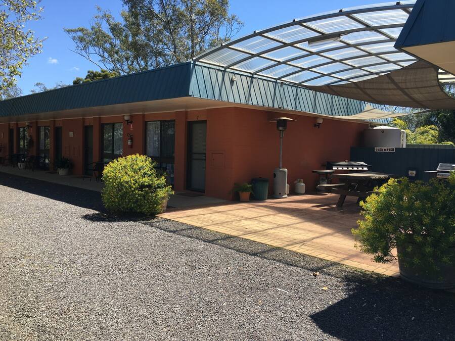 Un edificio con un espacio al aire libre techado, un depósito de agua y asientos exteriores.