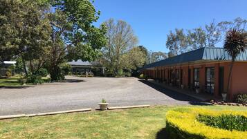 A building with a gravel driveway, surrounded by trees and a well-maintained lawn.
