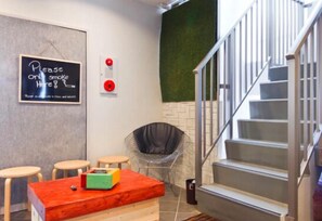 Ein modernes Interieur mit einer Treppe, einem Tisch mit roter Tischplatte, einem schwarzen Stuhl und einem Schild an der Wand.