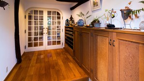 A wooden-floored hallway with a door leading to a room, shelves with various items, and a potted plant on the wall. - Pension EastMountain Hakuba (Hakuba)