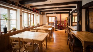 A restaurant with wooden tables and chairs, large windows, and a brick wall in the background. - Pension EastMountain Hakuba (Hakuba)