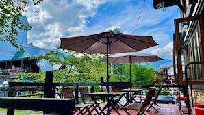 An outdoor patio with tables and chairs, umbrellas, and a brick floor. - Pension EastMountain Hakuba (Hakuba)