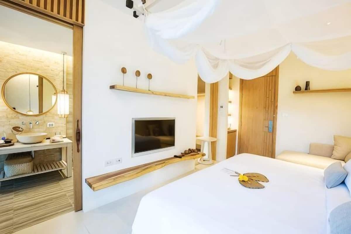 Un dormitorio moderno con una cama grande, un televisor montado en la pared, un tocador con espejo y un estante de madera.
