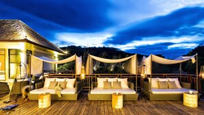 A wooden deck with three wicker sofas and cushions, a lamp, and a small table. - The Series Resort Khaoyai (Pak Chong)