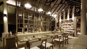 A long dining table with multiple chairs, a high ceiling with exposed beams, and a series of hanging light fixtures. - The Series Resort Khaoyai (Pak Chong)