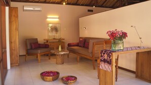 Una sala de estar acogedora con techo de madera, un conjunto de sofás, una mesita de centro y un jarrón con flores.