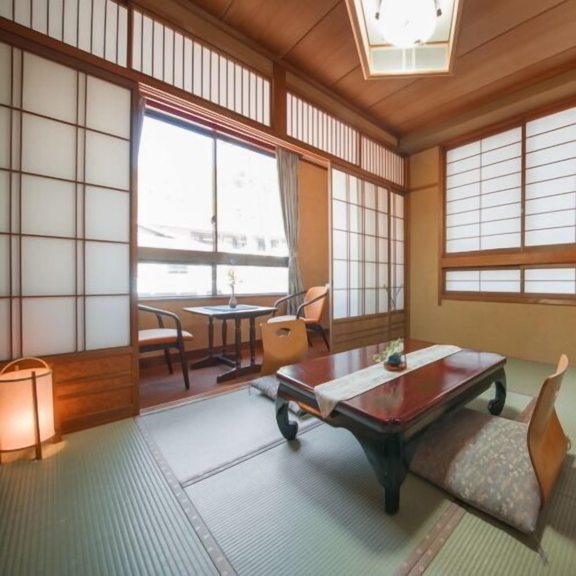 A traditional Japanese room with tatami flooring, a low table, and sliding doors.