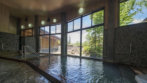 An indoor swimming pool with stone flooring, large windows, and a view of the outdoors. - Nakamurakan (Takayama)