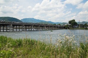 A wooden bridge over a river with mountains in the background. - Mulan Hostel (Kyoto)