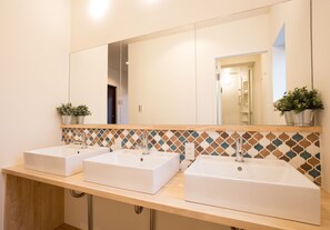 A bathroom with three white sinks, a large mirror, and a tiled backsplash. - Mulan Hostel (Kyoto)