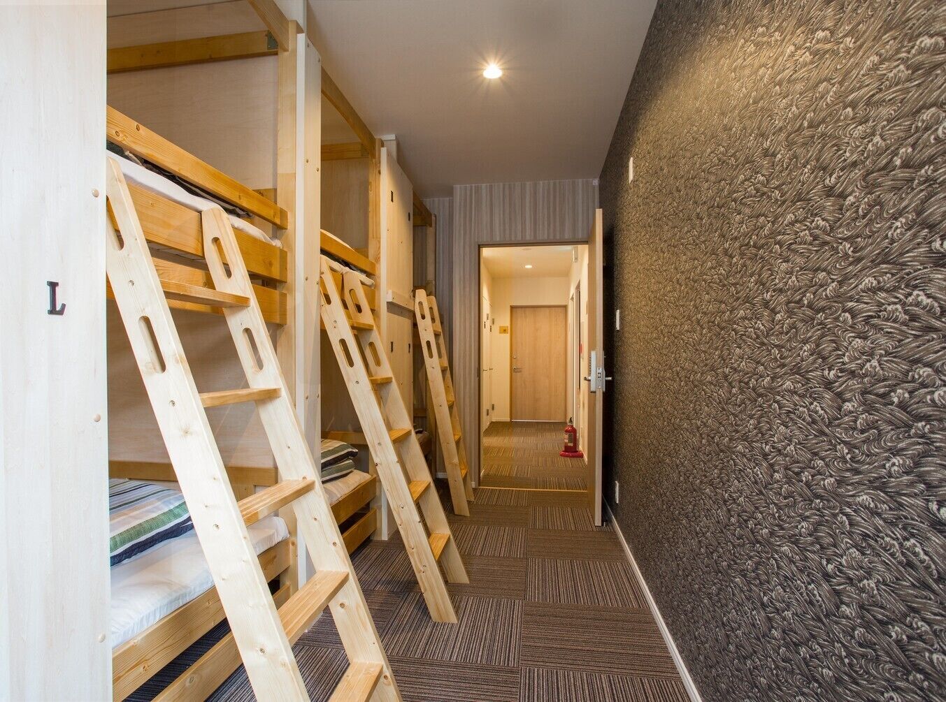 A narrow hallway with bunk beds on one side and a textured wall on the other.