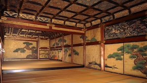 A traditional Japanese room with tatami flooring, sliding doors, and intricate woodwork on the ceiling and walls. - Mulan Hostel (Kyoto)