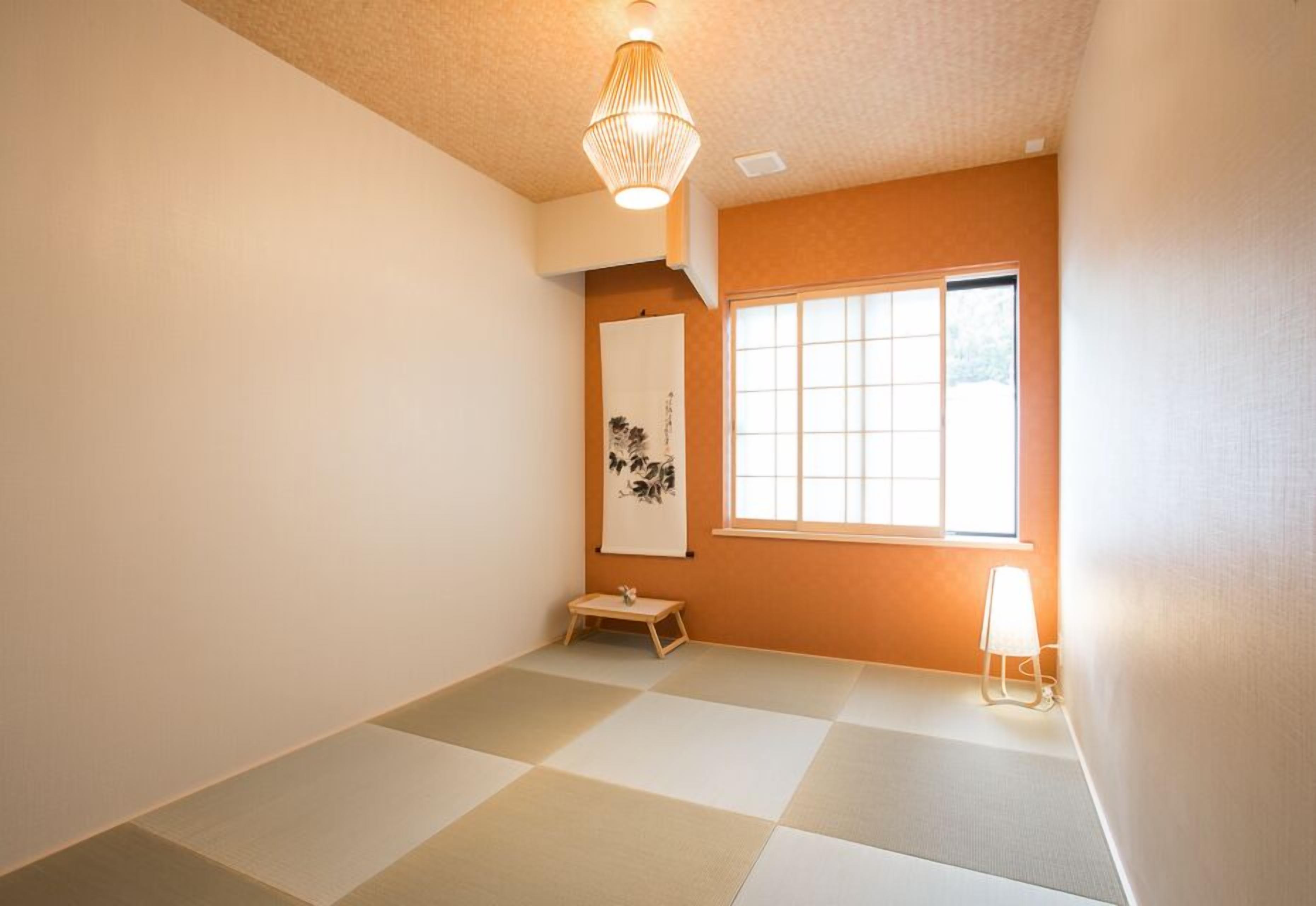 A room with tatami flooring, a shoji screen, a hanging scroll, and a small table.