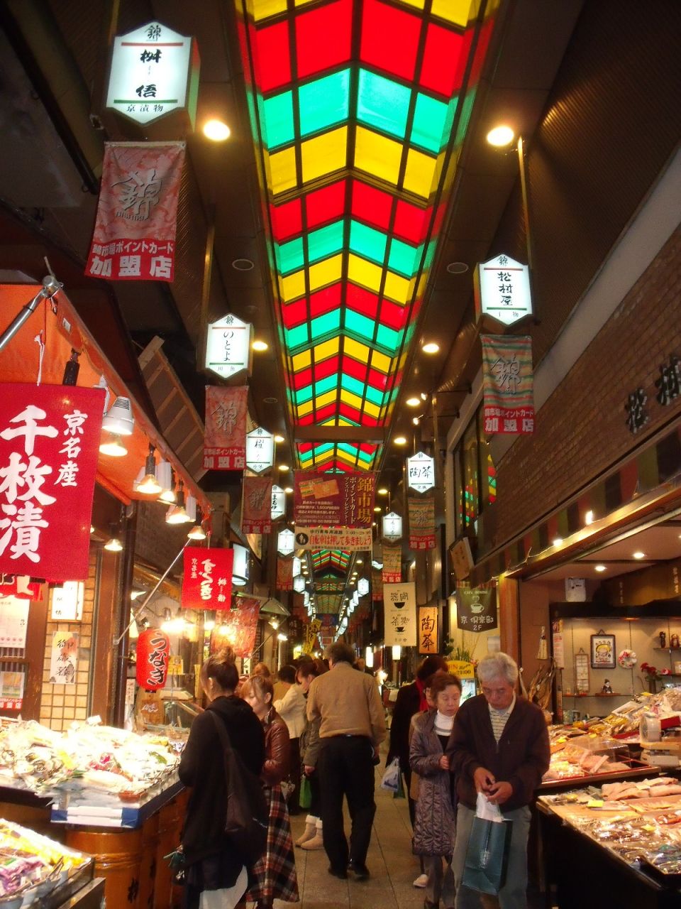 An indoor market with various stalls and hanging signs.