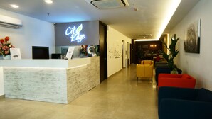 A hotel reception area with a marble counter, a neon sign, and a seating area with colorful sofas. - City Edge Hotel (Kuala Lumpur)
