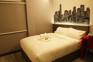 Una habitación de hotel con una cama, un cuadro de un paisaje urbano, una mesita de noche y una silla roja.