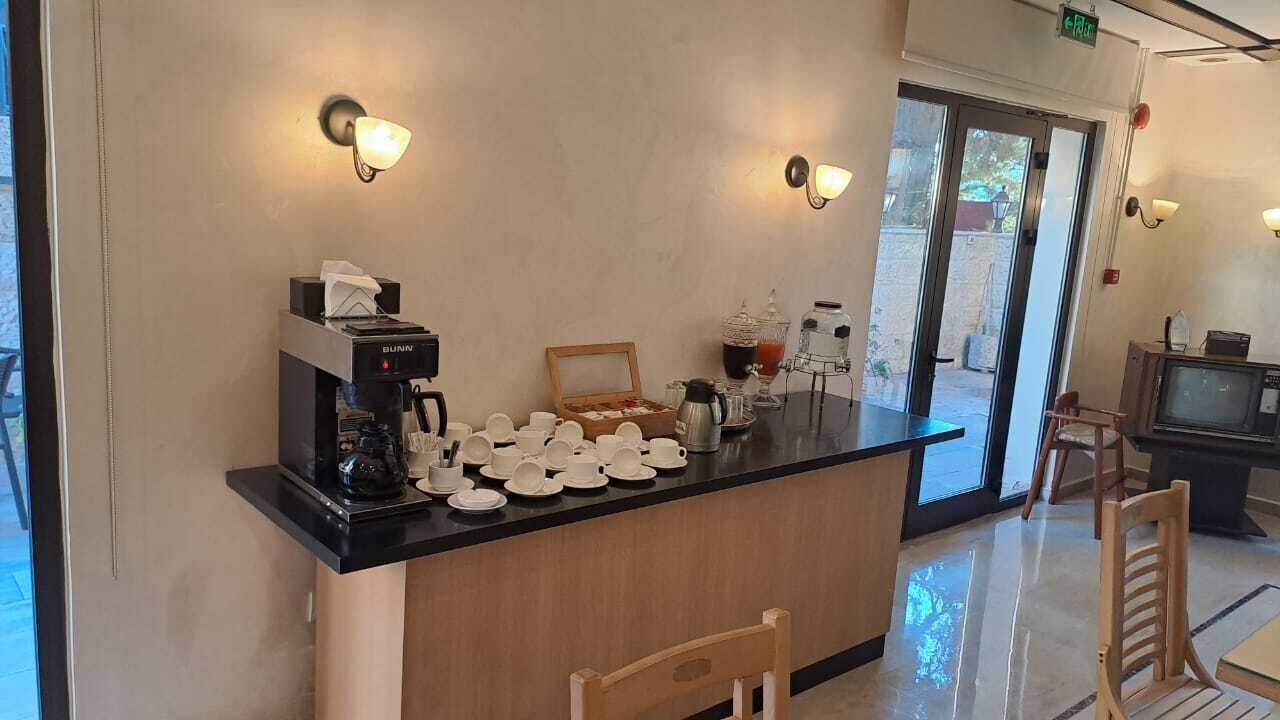 A coffee station with a coffee machine, cups, and a tray of pastries.