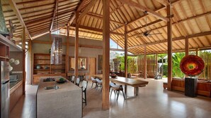 A spacious kitchen with a central island, wooden beams, and a large glass window. - Gahana Bali Villas (Seminyak)