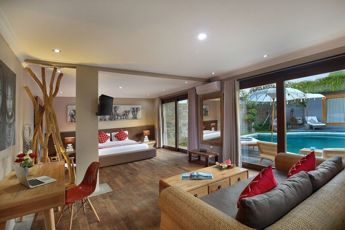 Una habitación de hotel moderna con una cama grande, un escritorio con una computadora portátil, un sofá y vistas a una piscina.