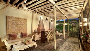An outdoor patio with a wooden ceiling, a sofa, a coffee table, and decorative items. - Gahana Bali Villas (Seminyak)