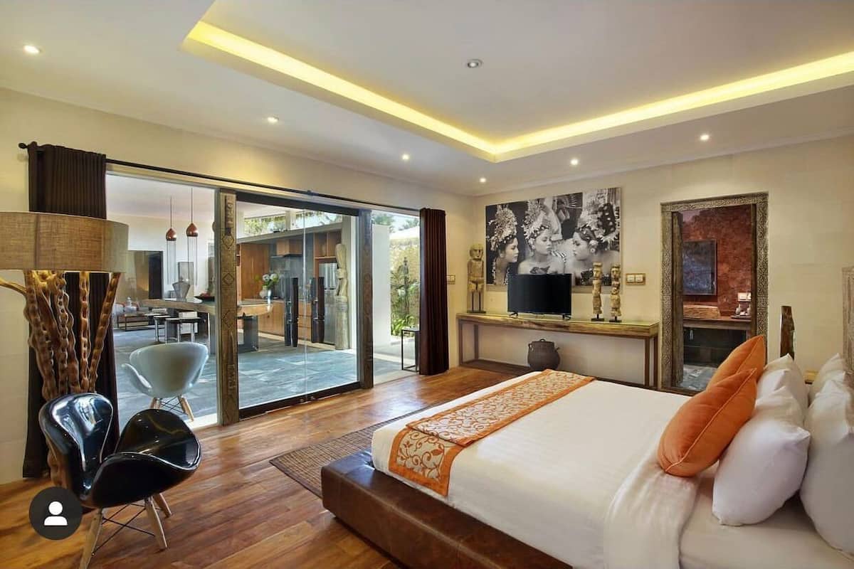 Una habitación de hotel moderna con una cama grande, televisión y vista al exterior.