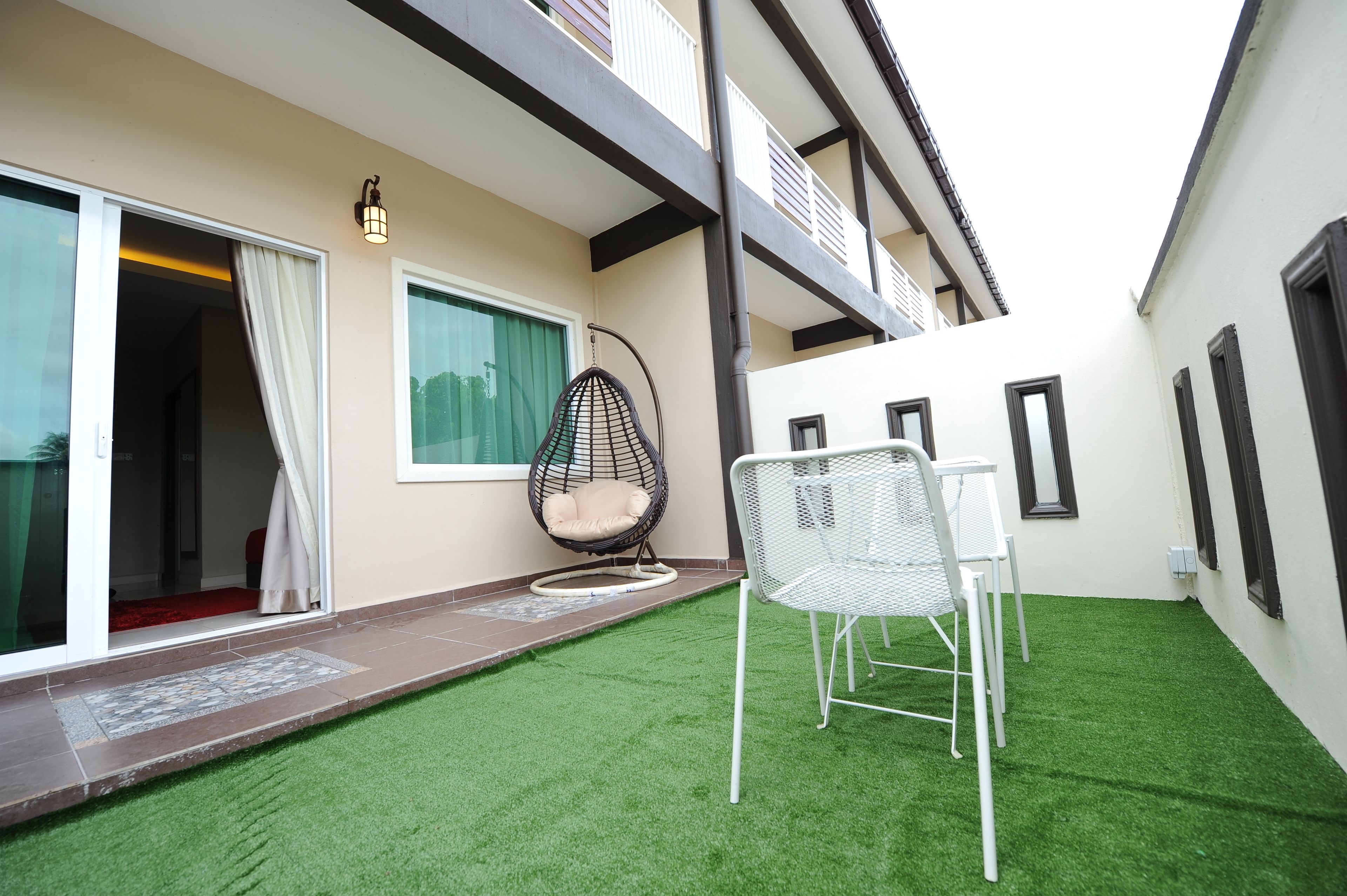 A modern outdoor patio with artificial grass, a hanging chair, and a table.