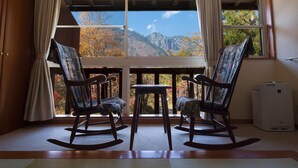 Ein Zimmer mit zwei Schaukelstühlen vor einem großen Fenster mit Blick auf die Berge.