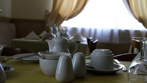 A dining table set with white ceramic tea set, including cups, saucers, and a teapot. - Invernook Hotel (Newquay)
