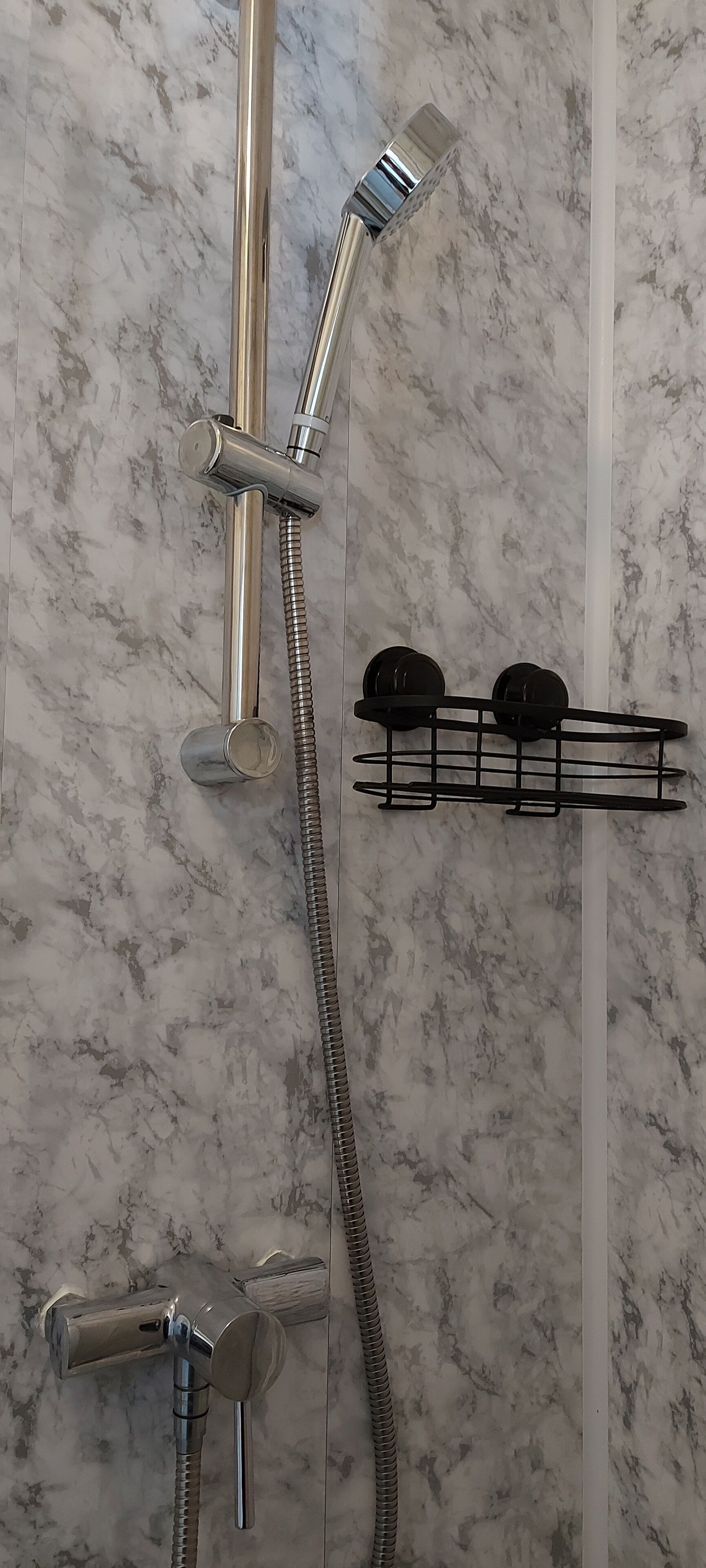 Une salle de bain équipée d’un système de douche comprenant un pommeau de douche à main, un pommeau de douche fixé au mur et un tuyau flexible.