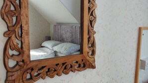 A wooden-framed mirror on a wall, a wooden desk with a remote control, and a notebook with a drawing. - Invernook Hotel (Newquay)