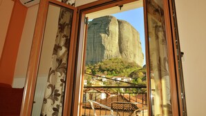 A room with a large window overlooking a mountain and a village. - Guesthouse Lithos (Kalabaka)
