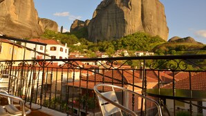 A balcony with a view of a large rock formation and a town below. - Guesthouse Lithos (Kalabaka)