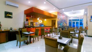 A restaurant with indoor seating, a counter, and a mural on the wall. - Front One Hotel Purwodadi (Purwodadi)