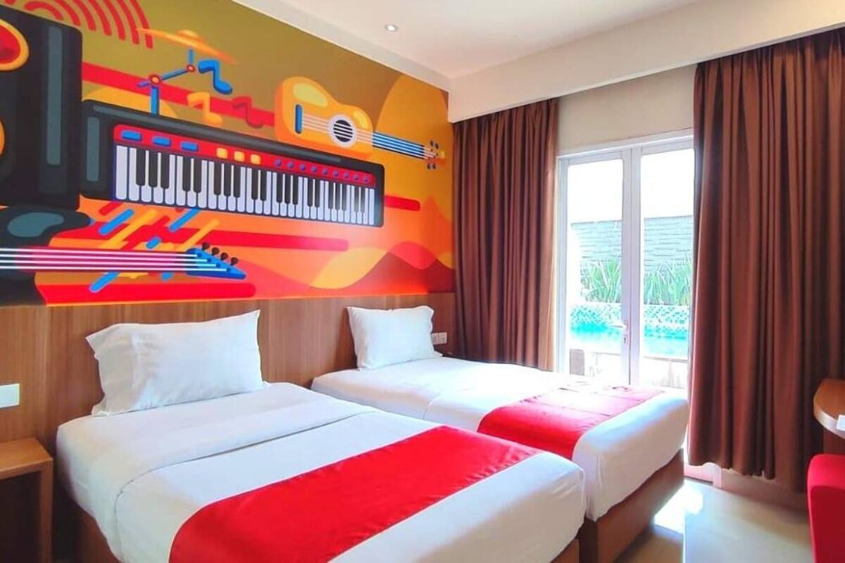 A hotel room with two beds, a TV, a desk with a chair, and a window with curtains.