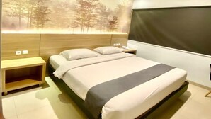 A modern bedroom with a large bed, a nightstand, a wall-mounted TV, and a mural of trees. - Front One Hotel Purwodadi (Purwodadi)
