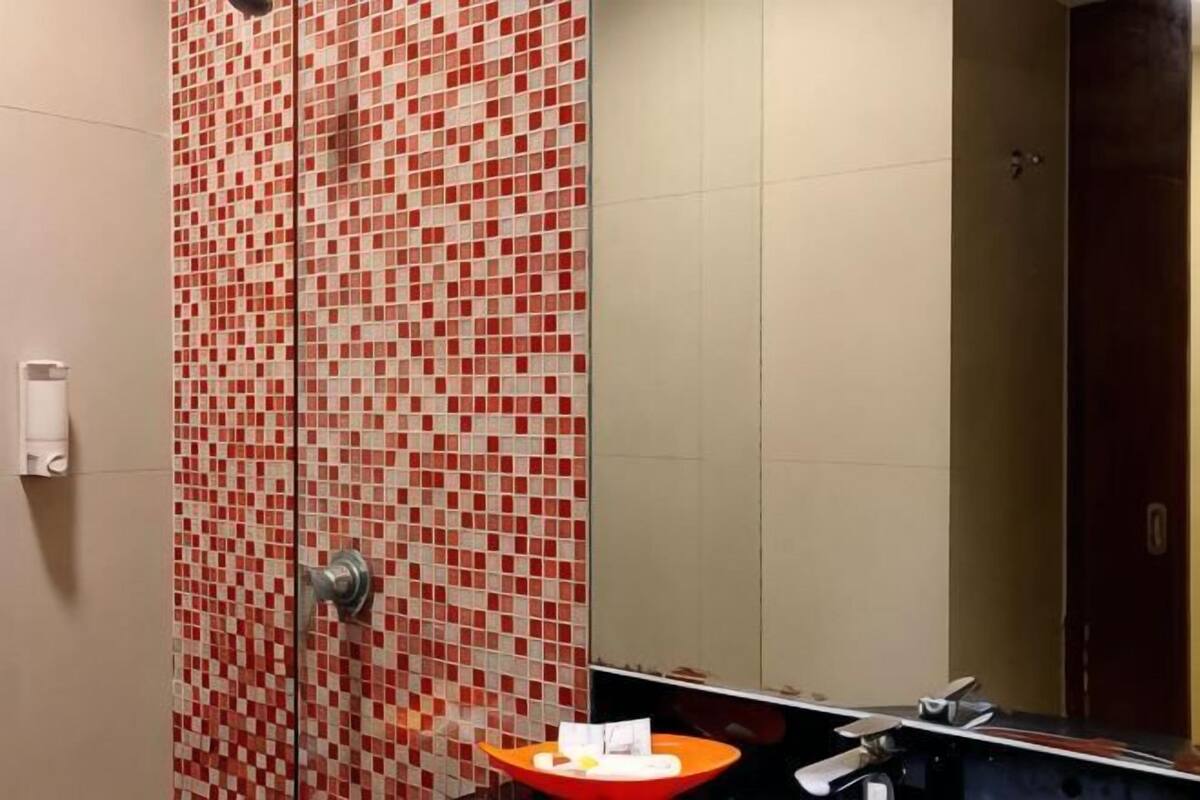 A bathroom with a tiled wall, a sink, and a mirror.